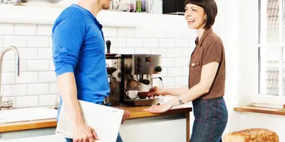 Deux personnes discutant devant une machine à café. 