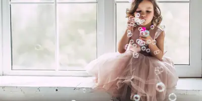 Une petite fille en costume de princesse rose fait des bulles