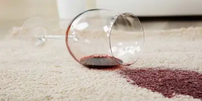 Verre à vin renversé sur un tapis créant une tache de vin