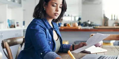 Une femme se concentre sur son travail à l'aide d'un ordinateur portable dans une pièce ensoleillée.